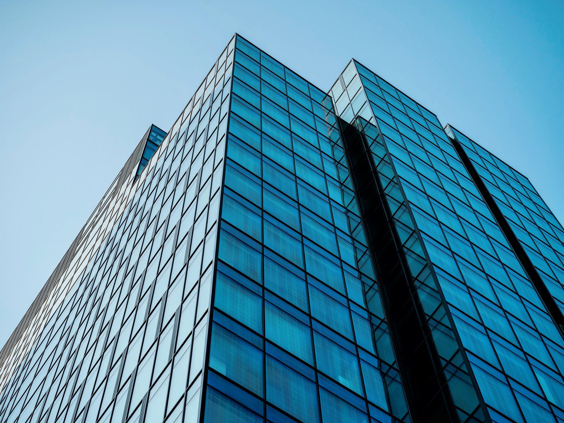 Glass office tower with blue reflective windows against a clear sky