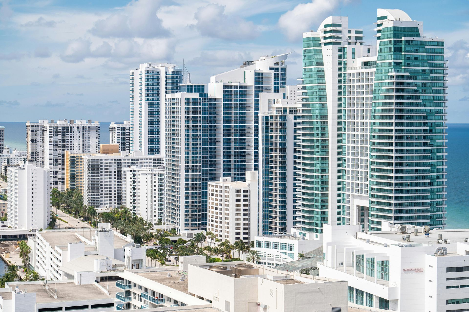 Modern high-rise waterfront buildings with white and turquoise towers under a clear blue sky