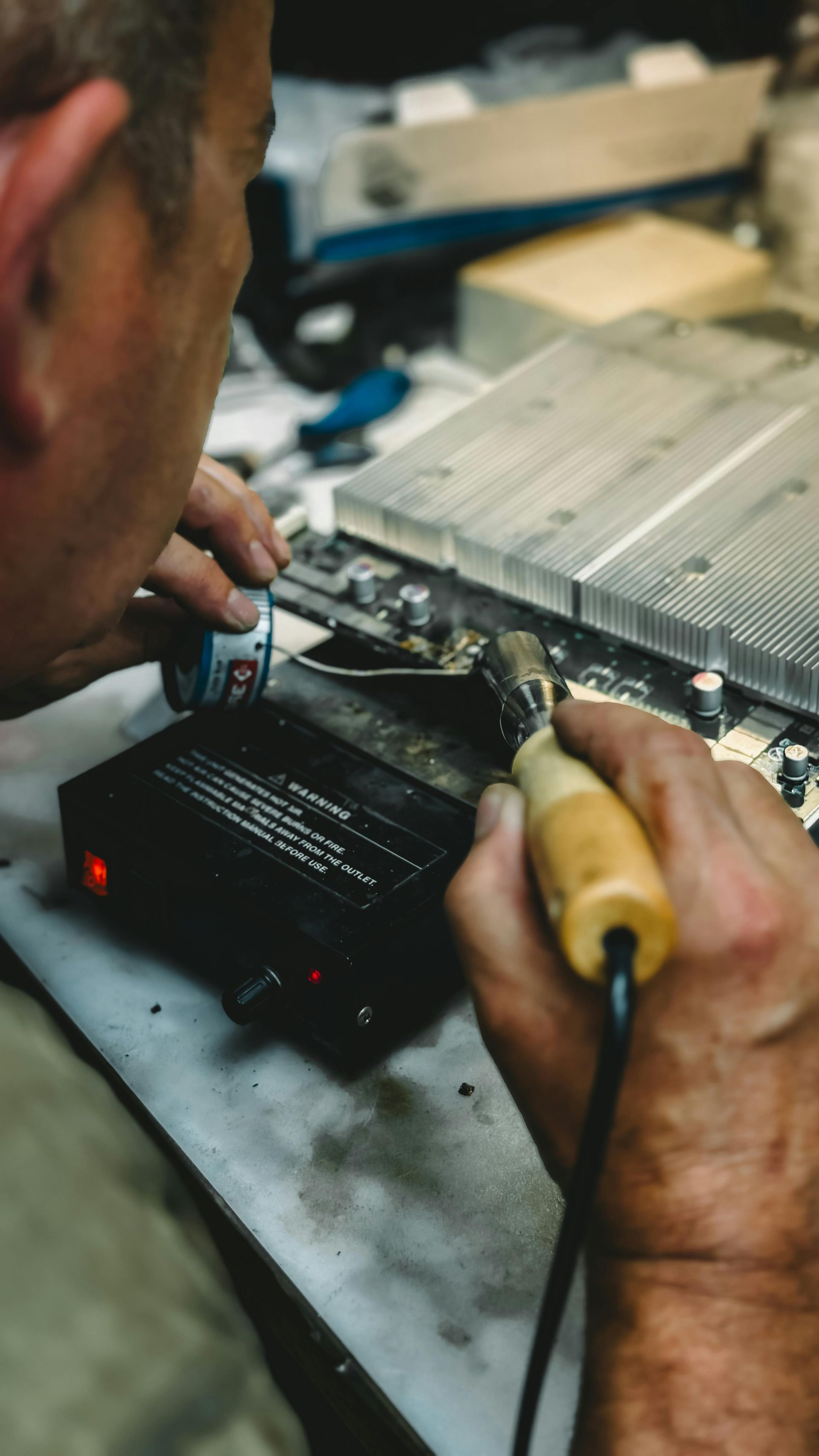 Technician repairing an electronic device with tools on a workbench