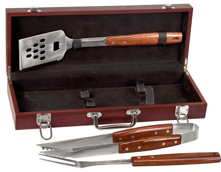 Wooden case with barbecue grill tools, including a spatula and tongs, laid out inside and in front