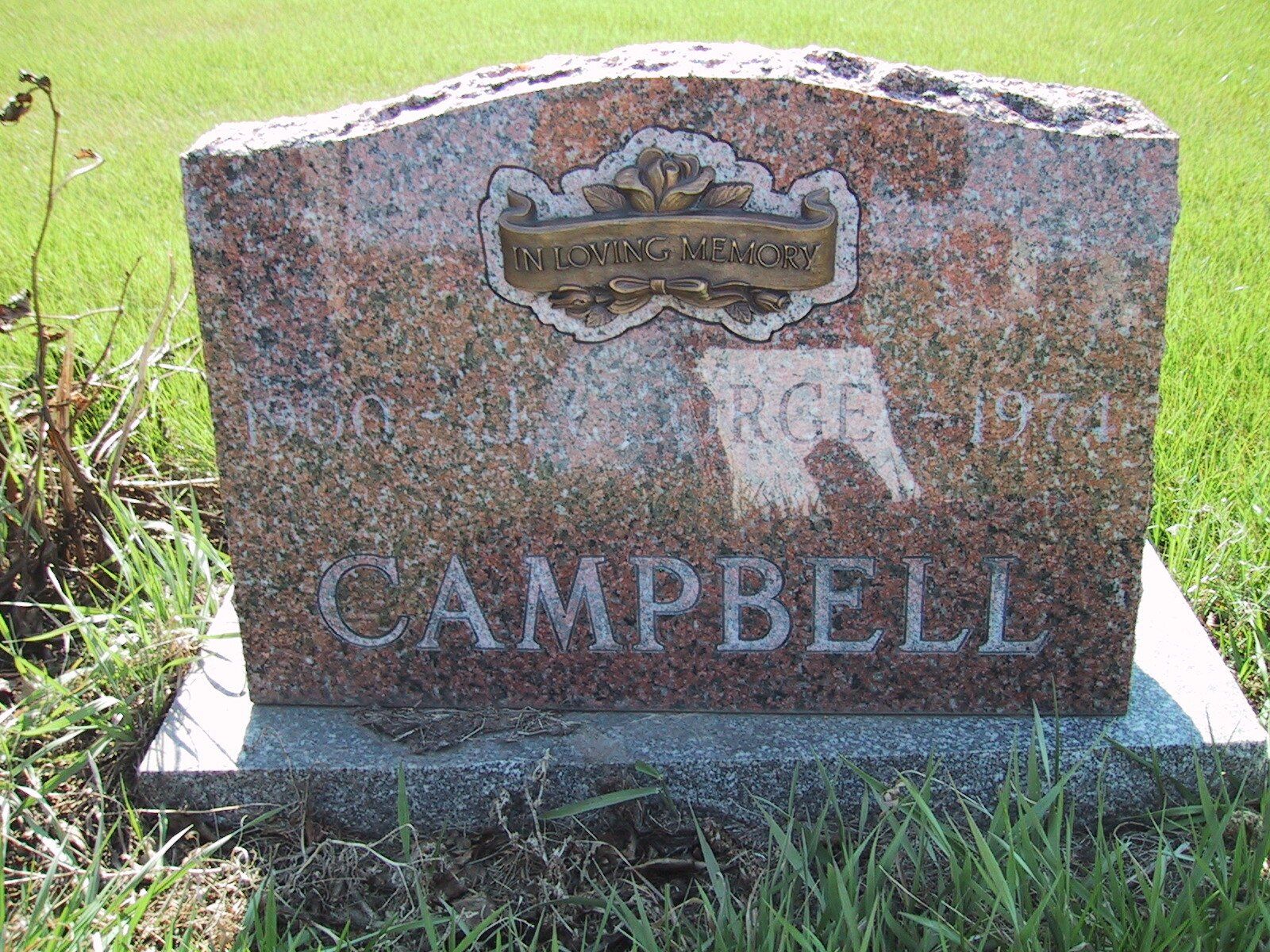 Close-up of a granite gravestone engraved with the name Campbell in a grassy cemetery.