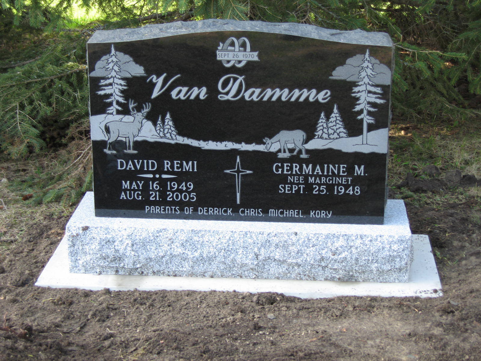 Black granite Van Damme memorial headstone with two names in a wooded cemetery