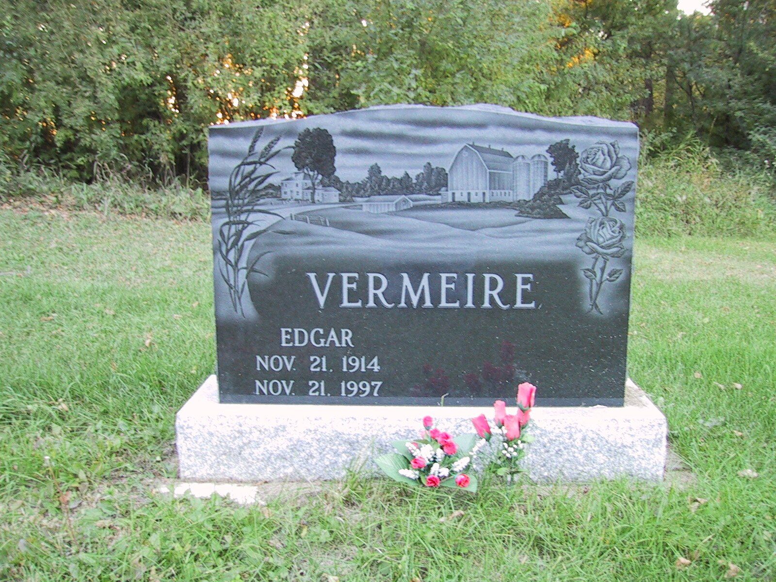 Gray VERMIRE gravestone in a grassy cemetery with flowers at the base