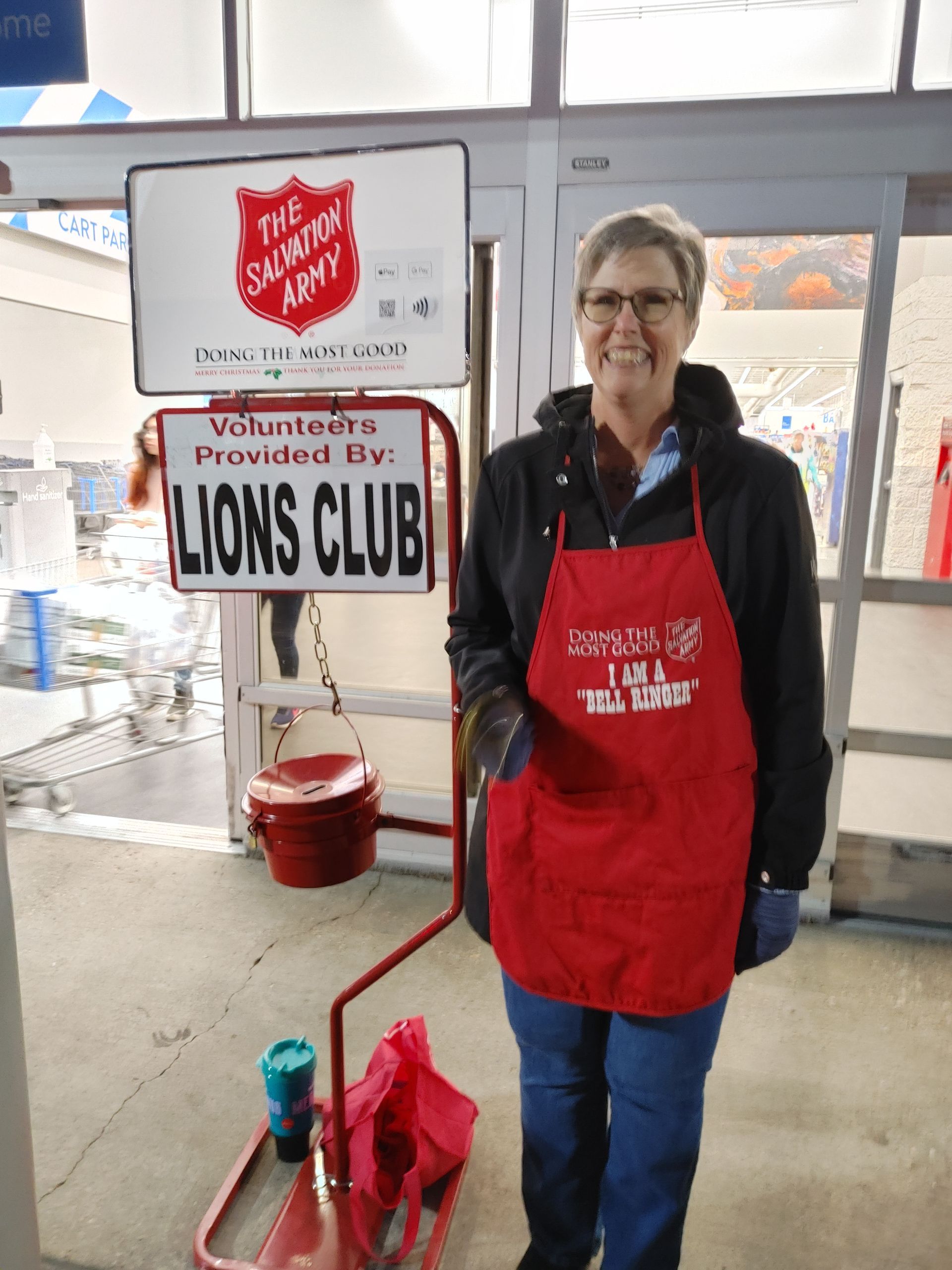 A woman in a red apron is standing in front of a sign that says lions club