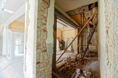 Interior under renovation with exposed walls, debris, and scaffolding in a hallway