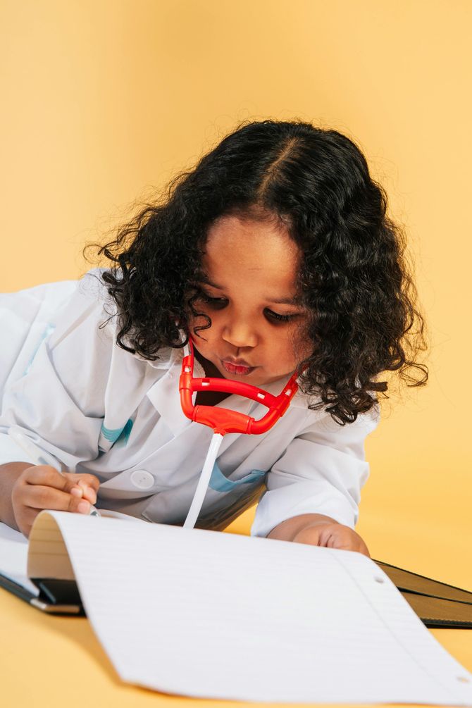 A little girl in a doctor costume is writing on a piece of paper.
