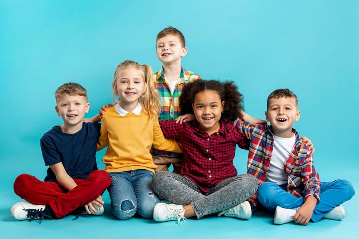 A group of children are sitting on the floor with their legs crossed.