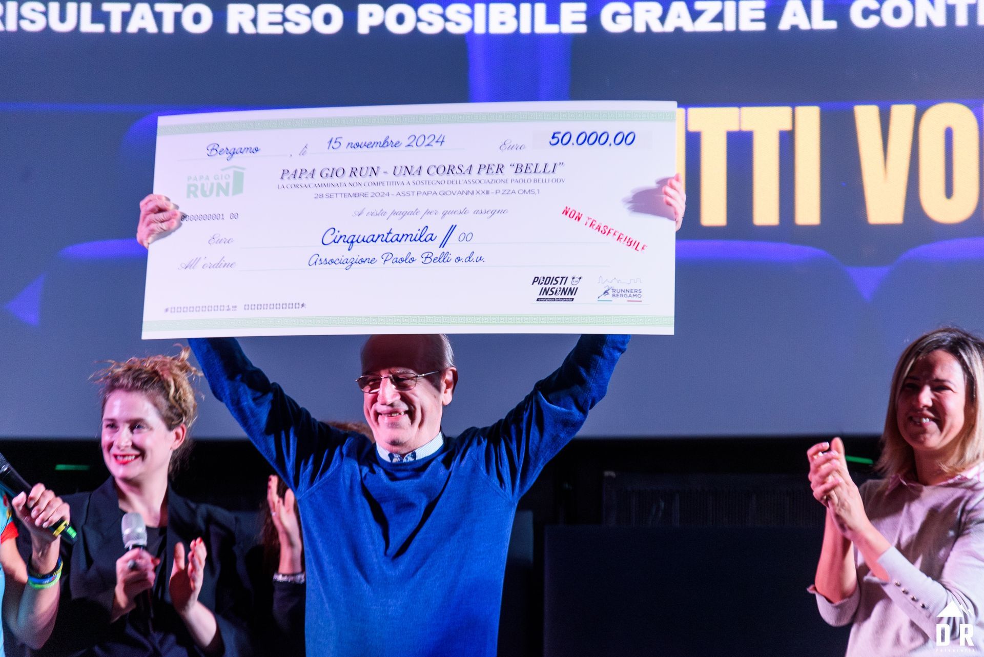 Foto di Silvano Manzoni, Presidente della Paolo Belli che mostra l'assegno ricevuto