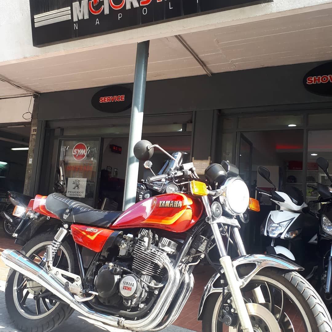 A red motorcycle is parked in front of a motorcycle shop