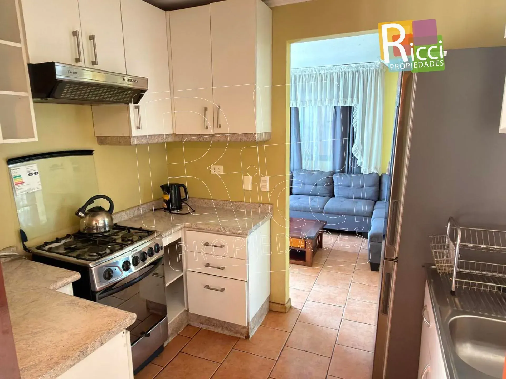 Casita con patio vallado en una esquina, bajo un cielo azul