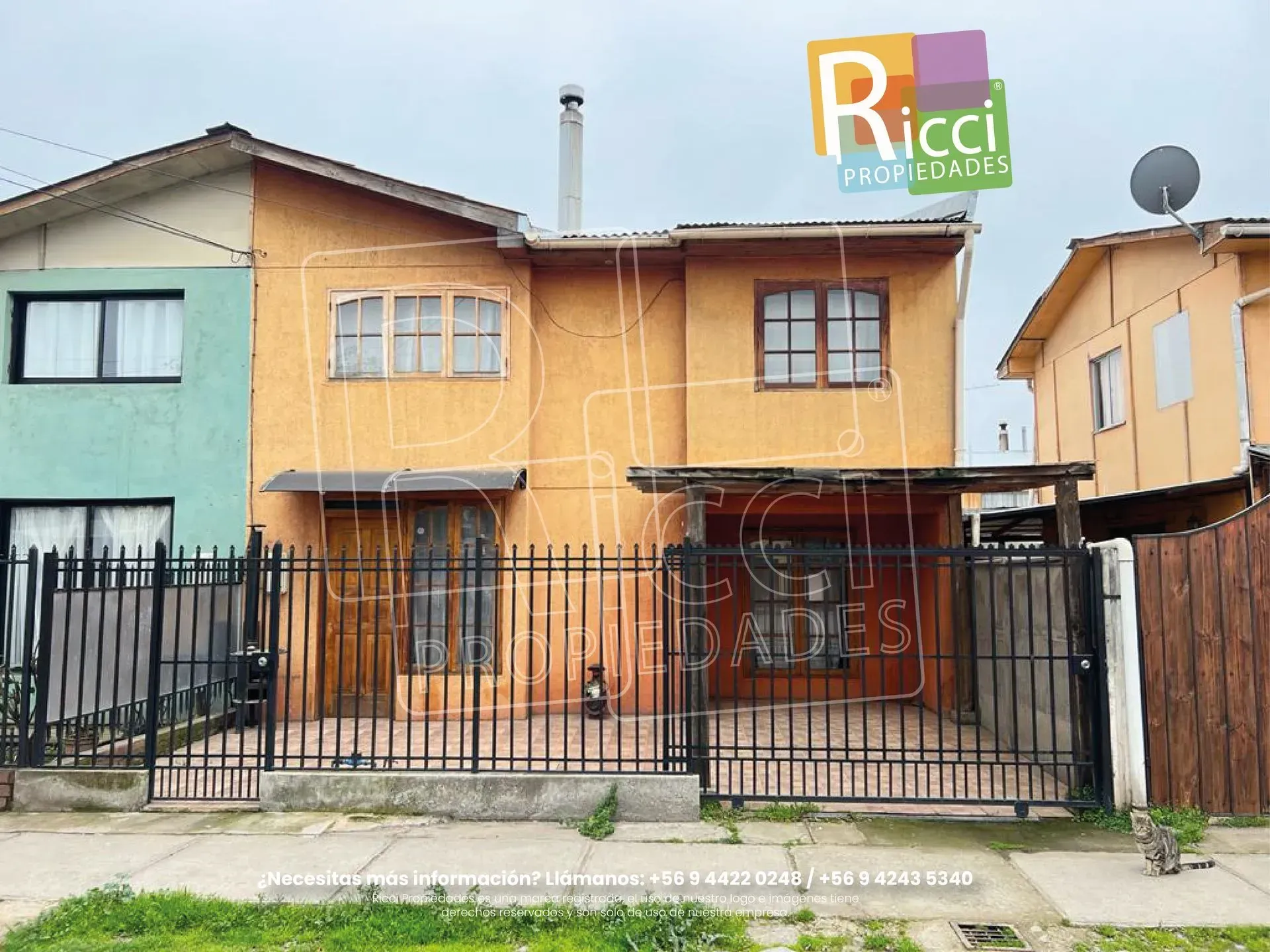 Casas coloridas de dos pisos detrás de una cerca de metal negro, con un letrero de la guardería Ricci en el techo.