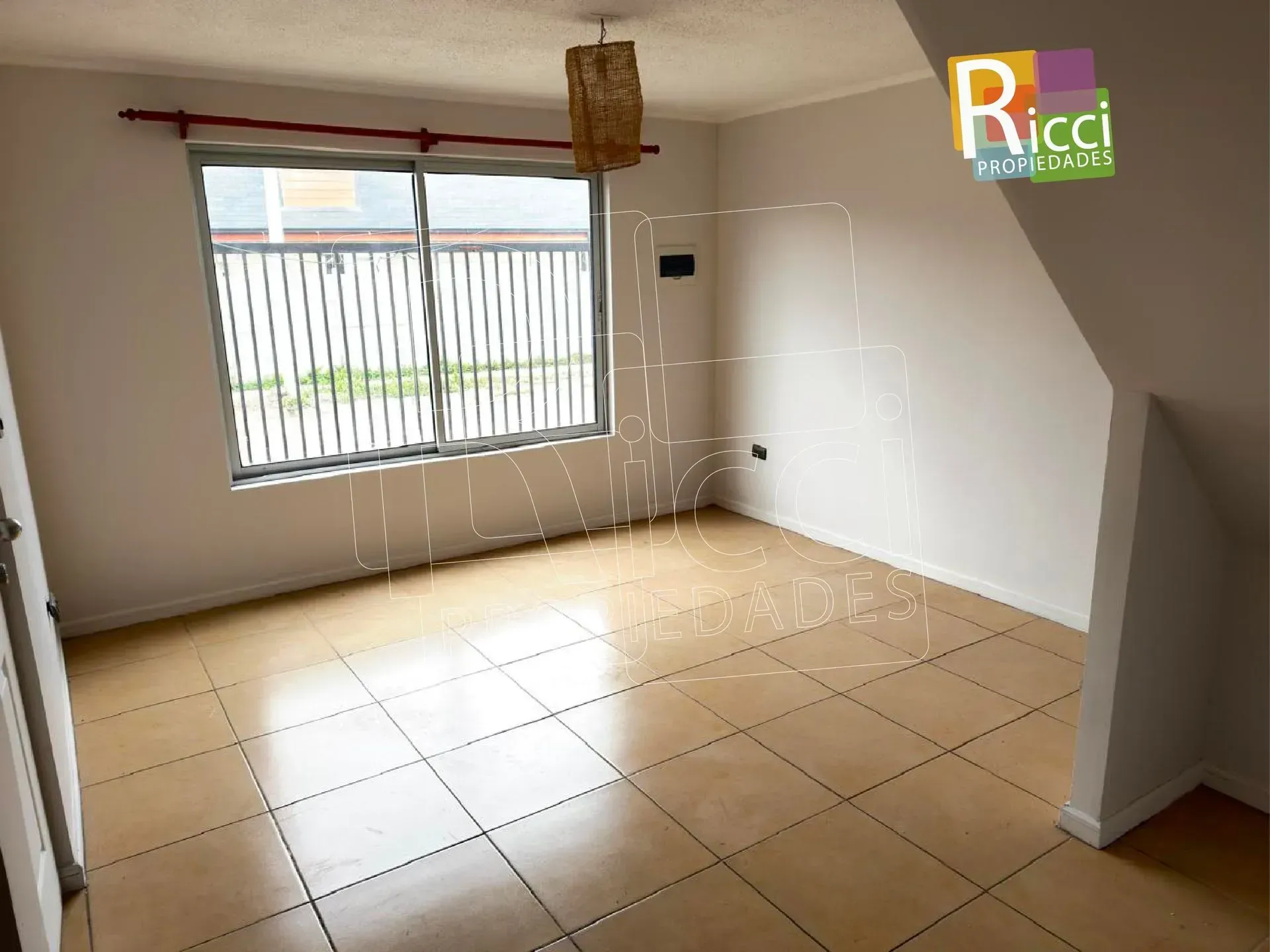 Vista frontal de una casa pequeña con revestimiento de madera, paredes inferiores amarillas y una cerca y un portón de metal negro