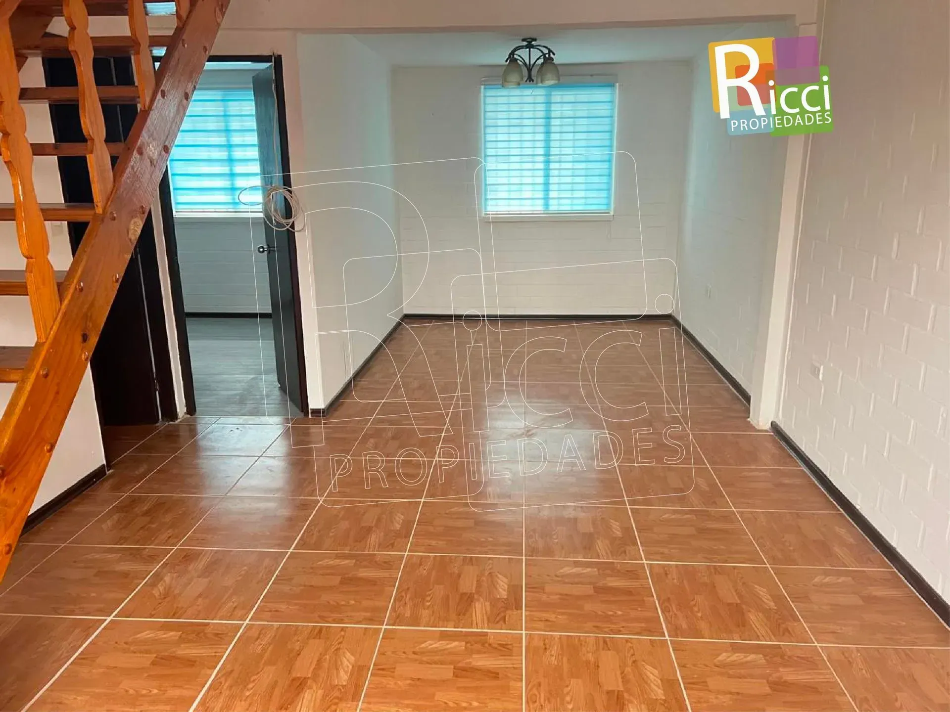 Casa blanca con valla metálica negra, pequeño jardín delantero y entrada pavimentada bajo guirnaldas de luces