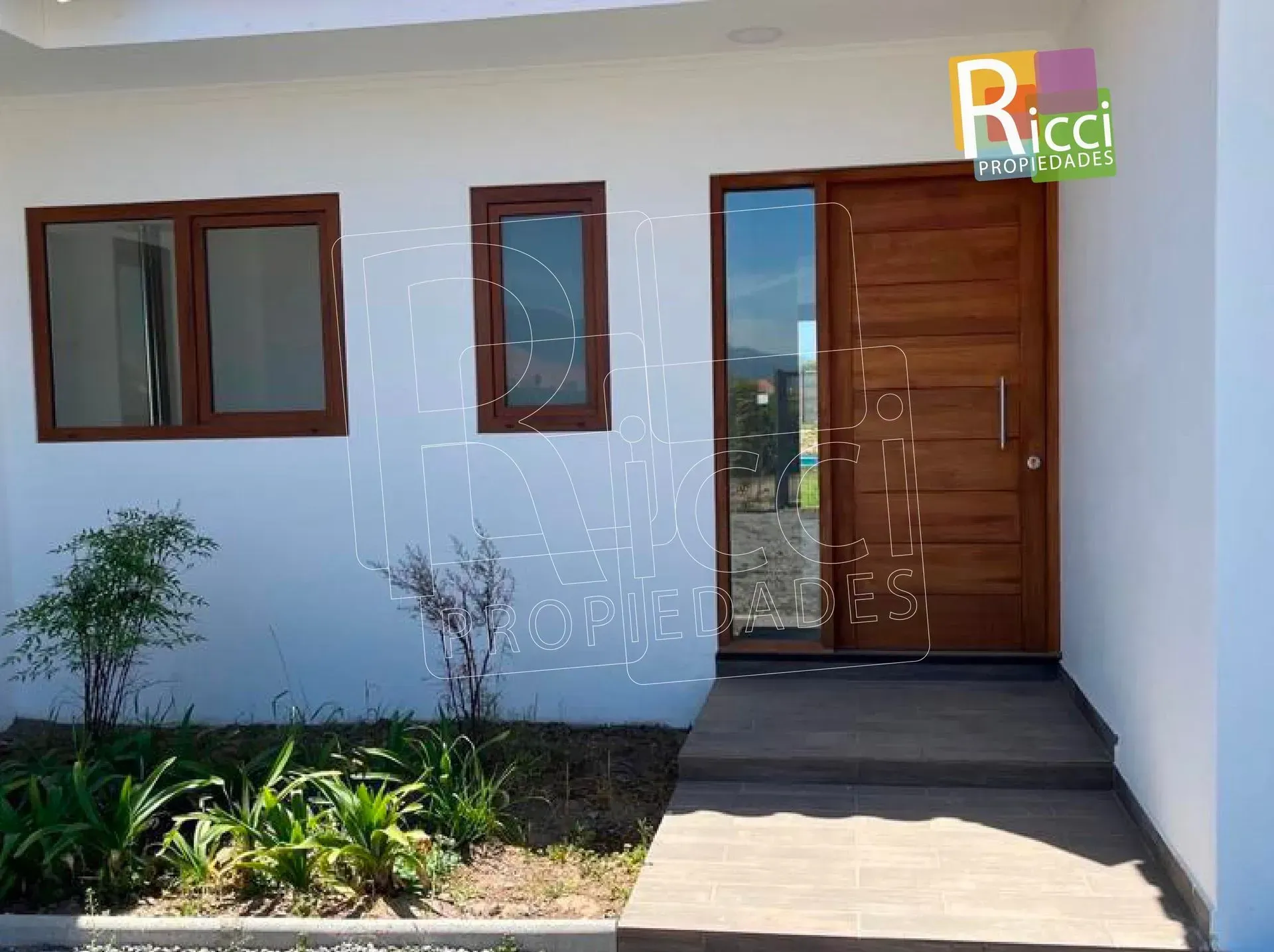 Moderna casa blanca con tejado de tejas rojas y entrada de grava bajo un cielo nublado