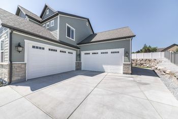 A newly built plain concrete driveway complements the grey-painted residential property in Perth WA.