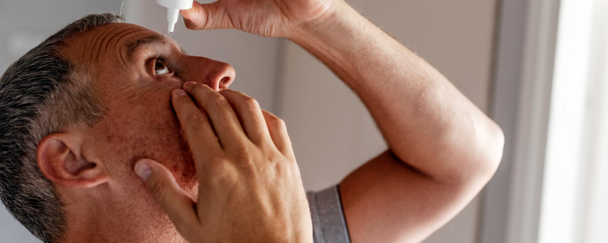 a man putting eye drops into eye