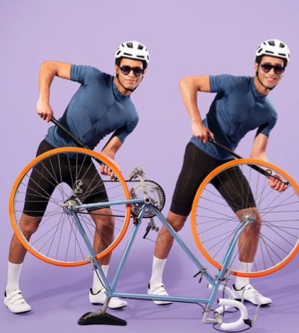 Two men are standing next to a bicycle on a purple background and wearing woow sunglasses