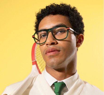 A man wearing woow
glasses and a green tie is holding a tennis racquet