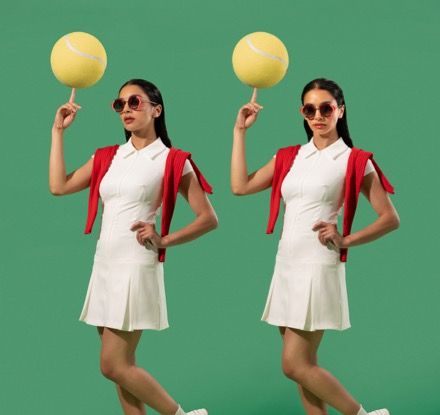A woman in a white dress is holding a tennis ball on a stick.