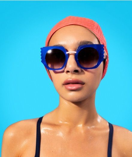 a woman in an orange bay=thing cap and woow sunglasses
