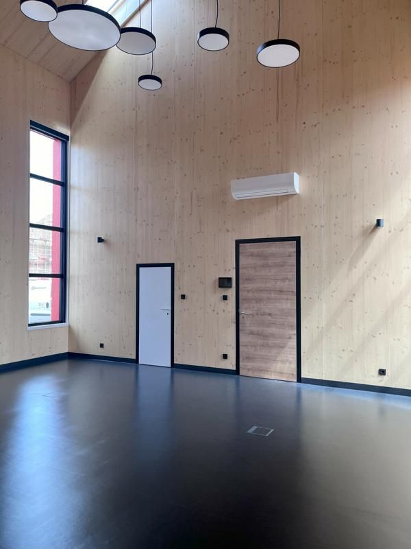Leeres, modernes Zimmer mit hohen Fenstern, holzgetäfelten Wänden und runden Deckenleuchten