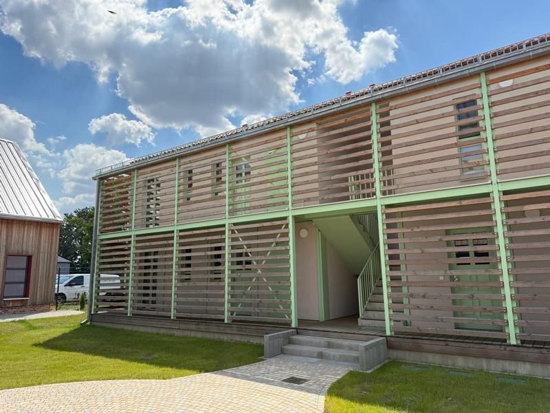 Zweistöckiges Holzgebäude mit grünen Zierelementen und Lattenbalkonen unter einem bewölkten Himmel