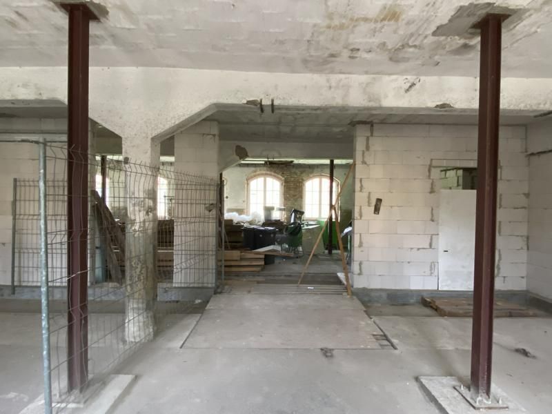 Unfertiger Innenraum mit Betonboden, weißen Wänden und im Bau befindlichen Metallstützpfosten