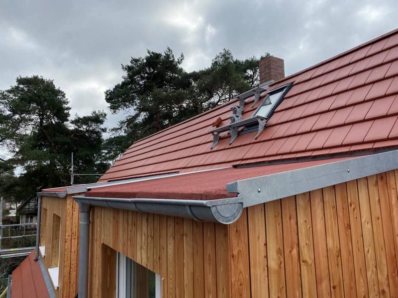 Kleines Holzgebäude mit rotem Ziegeldach und Oberlicht unter bewölktem Himmel