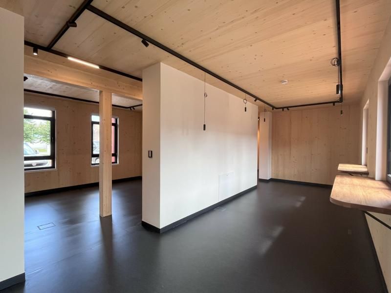 Leeres, modernes Zimmer mit schwarzem Boden, weißen Wänden, Holzdecke und großen Fenstern