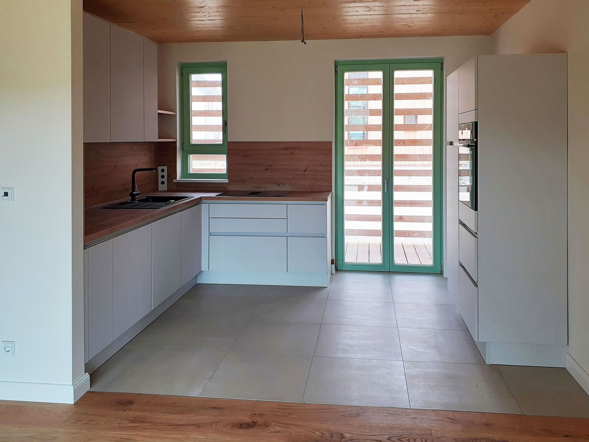 Moderne weiße Küche mit Holzelementen und grünen Zierleisten.