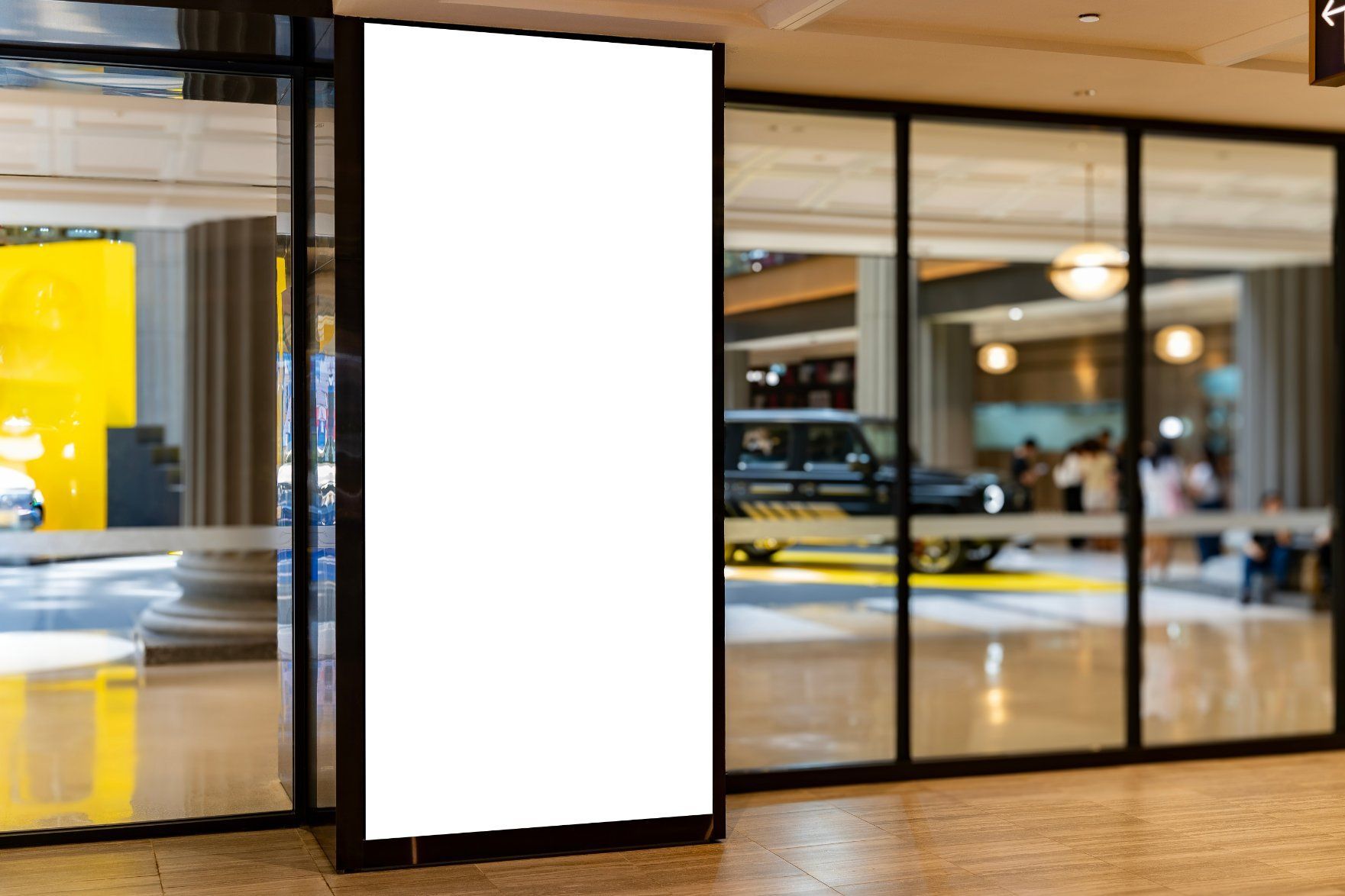 A White Billboard Is Sitting in Front of A Glass Door in A Shopping Mall — Renovo Contractors In Monash, ACT