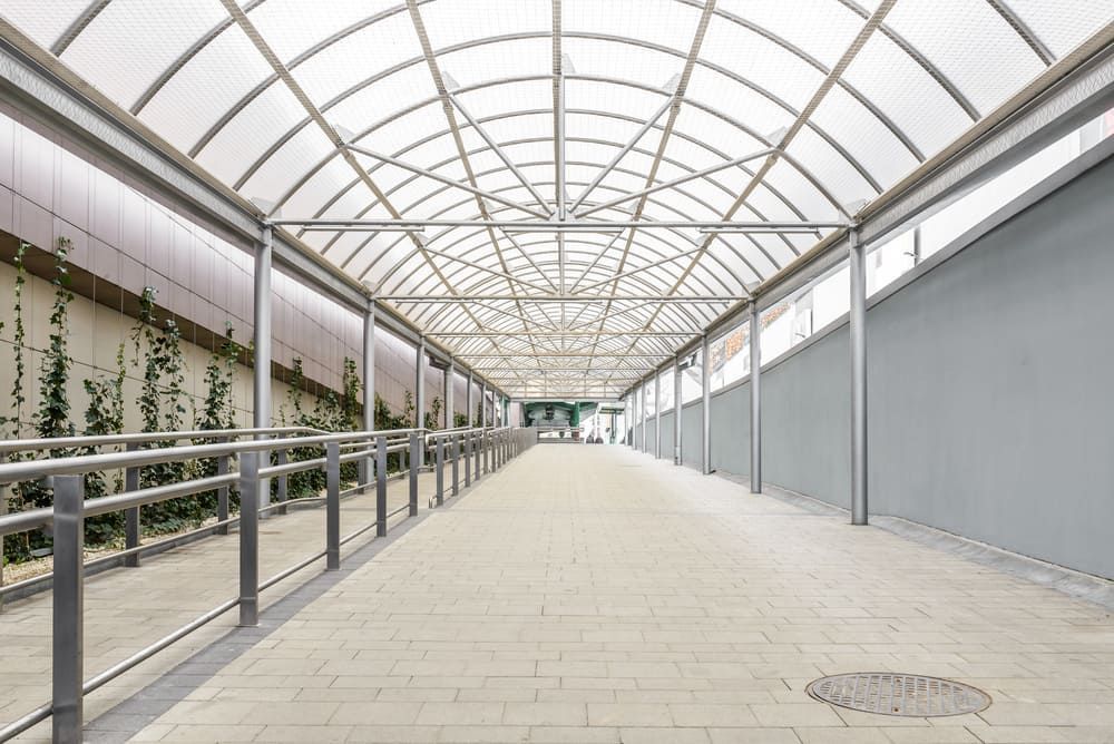 An Empty Walkway With A Clear Roof And A Railing — Renovo Contractors In Monash, ACT