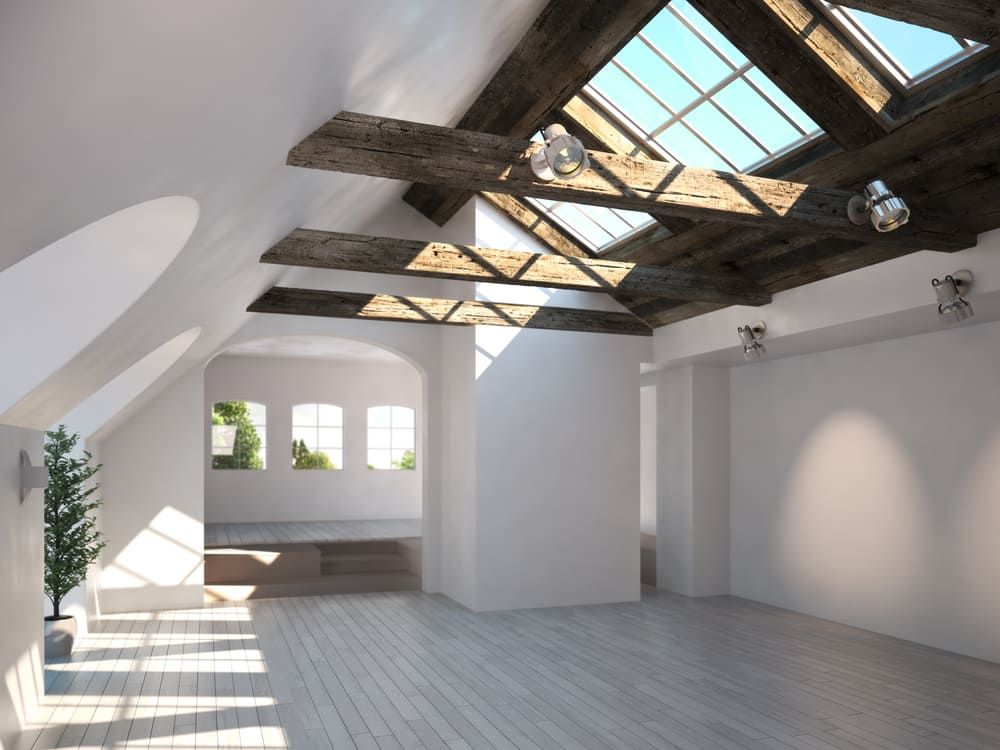 An Empty Room With a Skylight and Wooden Beams — Renovo Contractors in Queanbeyan, NSW