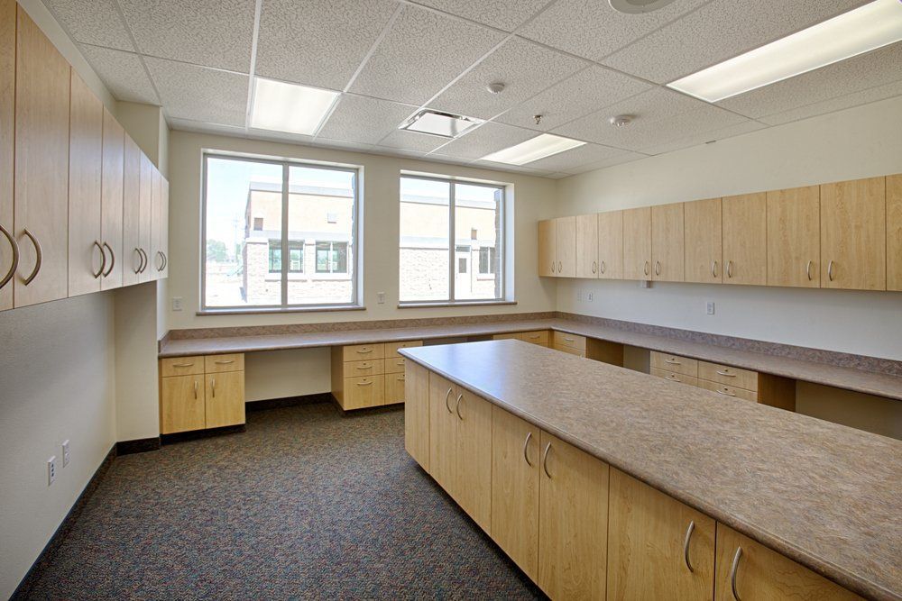 A Large Empty Room with Wooden Cabinets and Counter Tops — Renovo Contractors In Monash, ACT