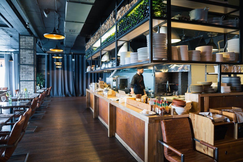The Interior of A Restaurant with Tables and Chairs and A Chef Preparing Food — Renovo Contractors In Monash, ACT