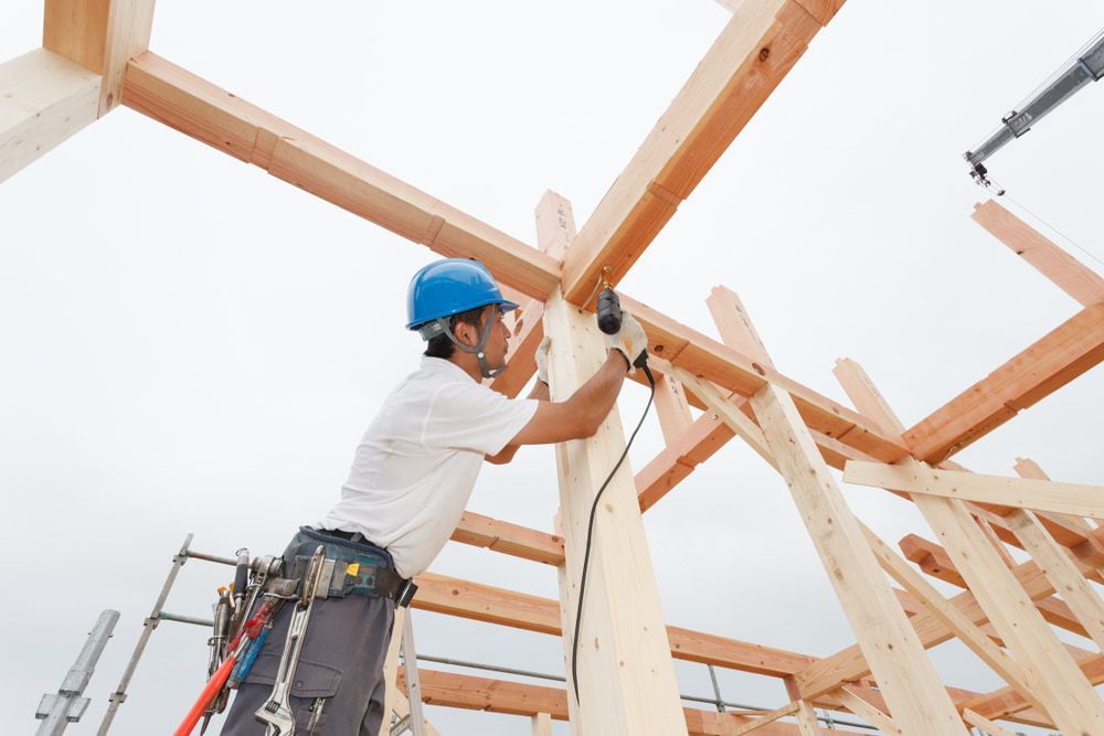 A Construction Worker Is Working On A Wooden Structure — Renovo Contractors In Monash, ACT