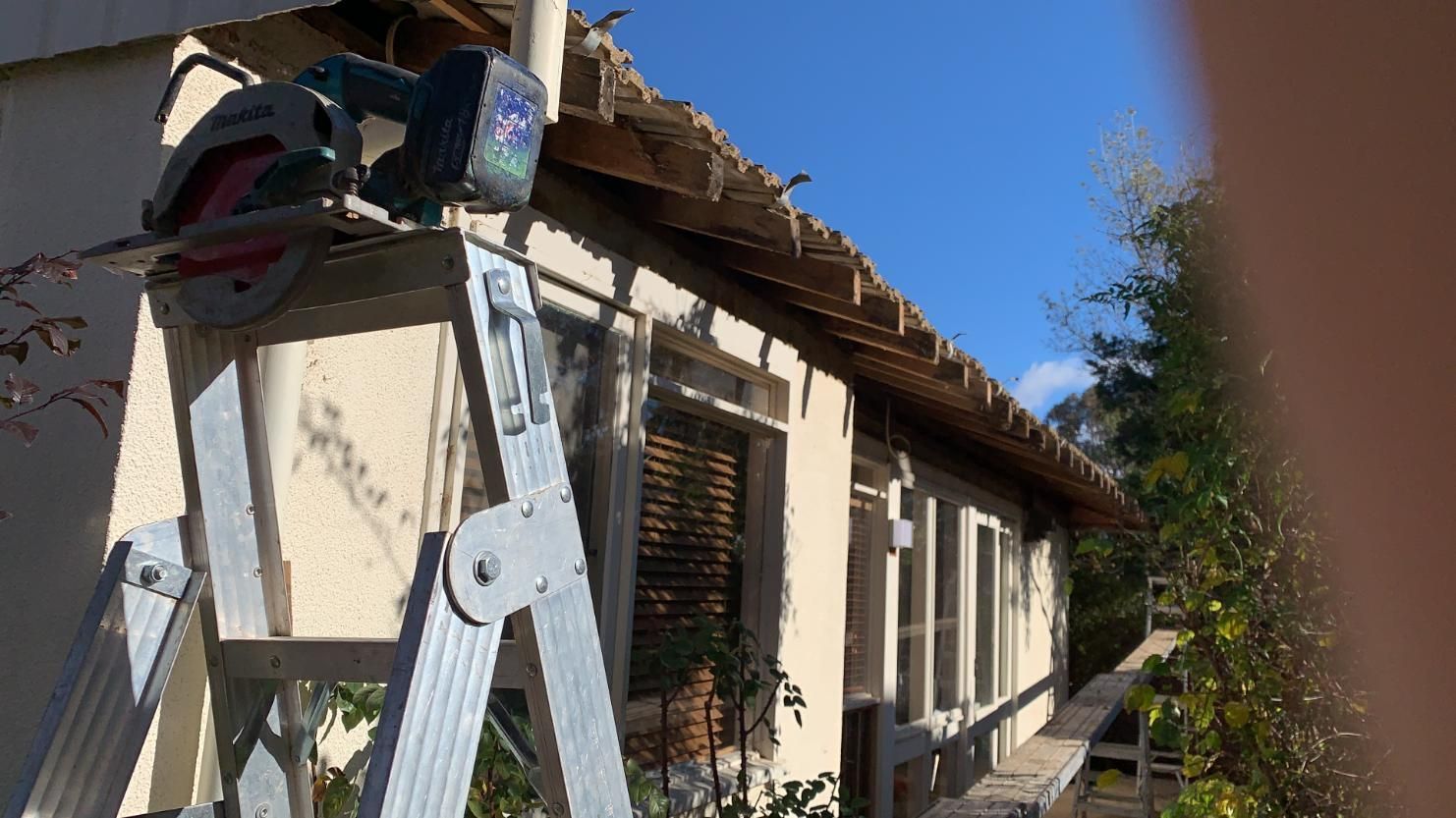 A Ladder Is Sitting Next To A Circular Saw On The Side Of A Building — Renovo Contractors In Monash, ACT