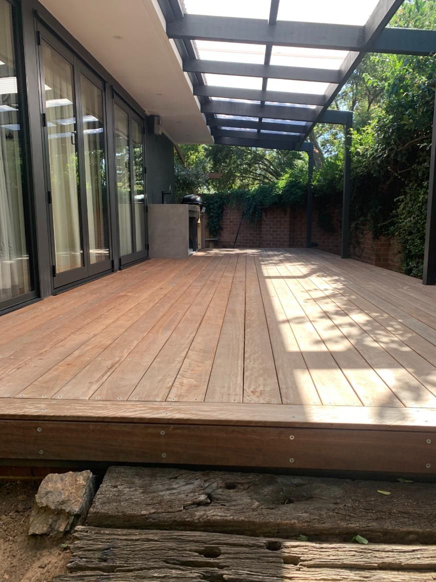 A Wooden Deck With A Pergola Over It In Front Of A House — Renovo Contractors In Monash, ACT