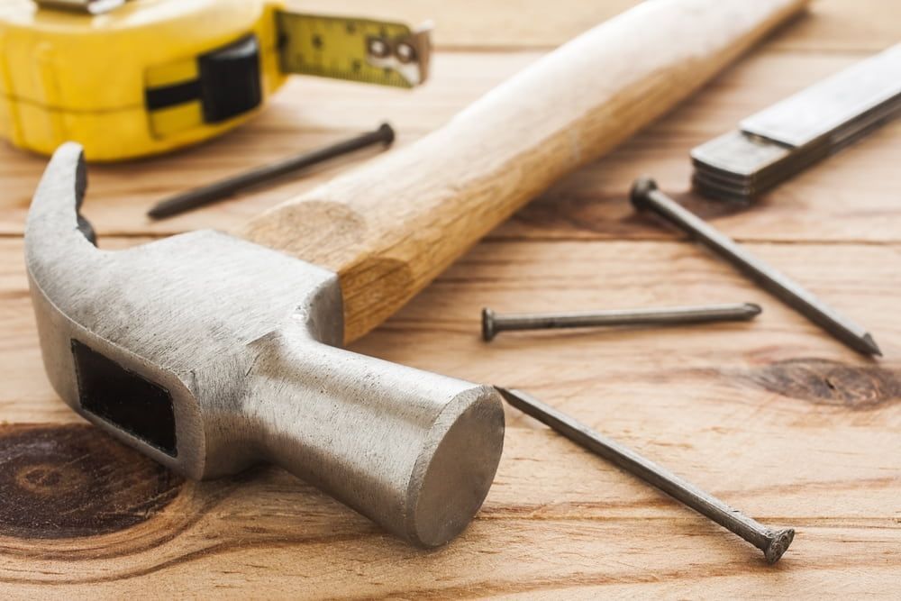 A Hammer And Nails Are On A Wooden Table — Renovo Contractors In Monash, ACT