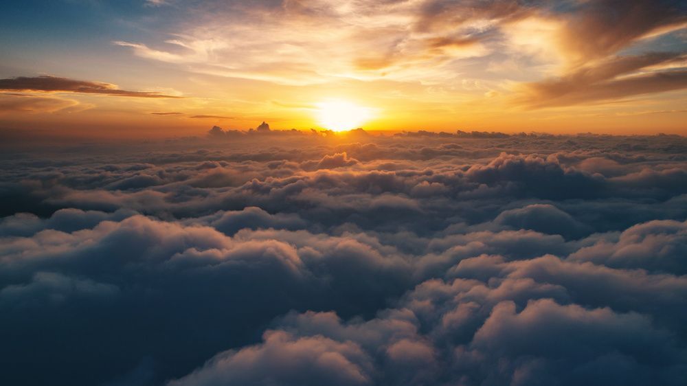 Sunrise glowing over a sea of clouds with orange and pink sky