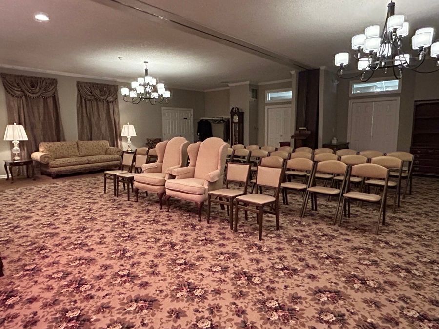 Elegant banquet room with rows of chairs, sofas, chandeliers, and patterned carpet