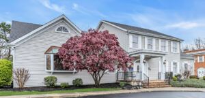 Suburban house with white siding and a pink flowering tree in the front yard