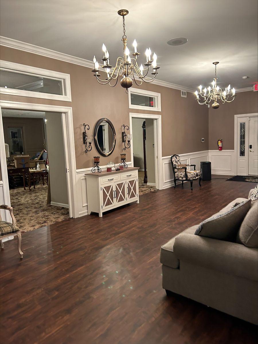 Elegant living room with chandeliers, hardwood floors, taupe walls, mirror console, and sectional sofa
