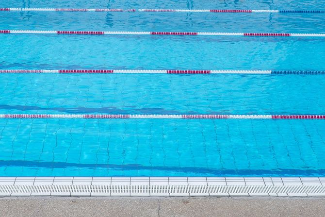 Swimming pool lanes with clear blue water and lane dividers, viewed from above.