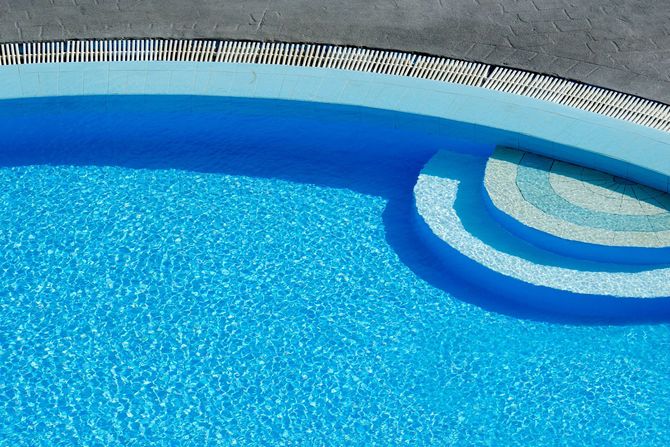 Blue swimming pool with curved steps and tiled edge