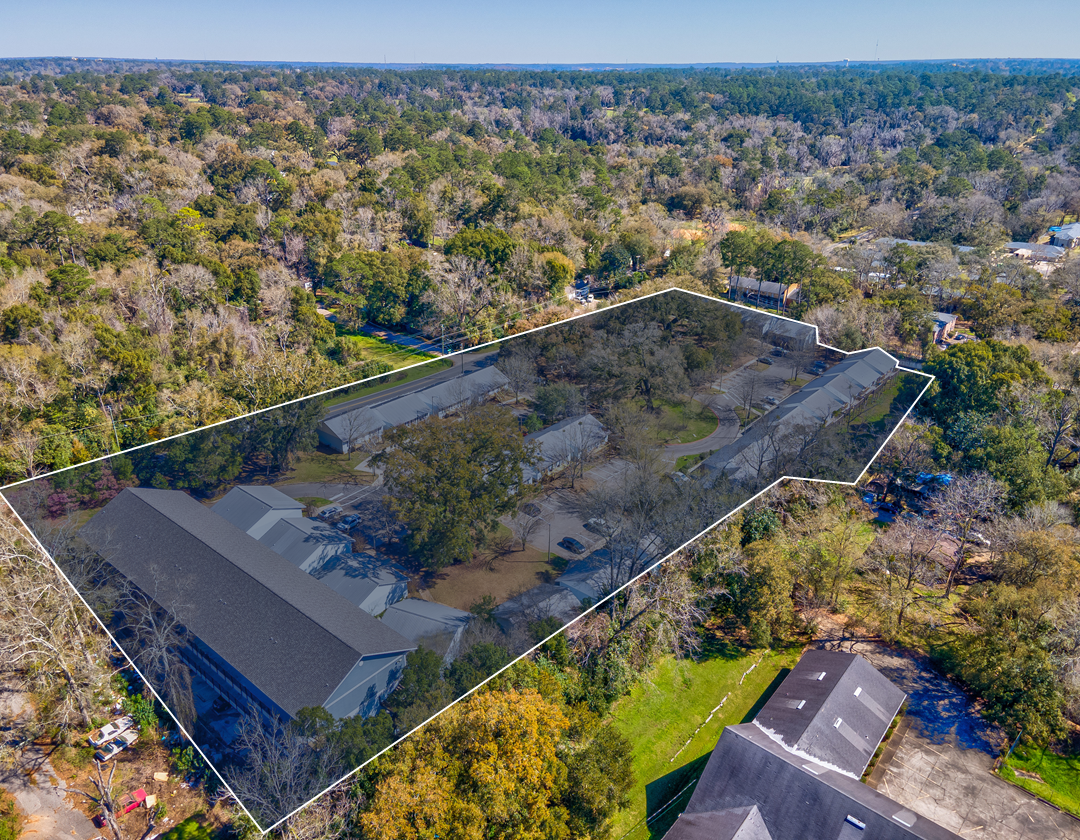 An aerial view of a house in the middle of a forest.