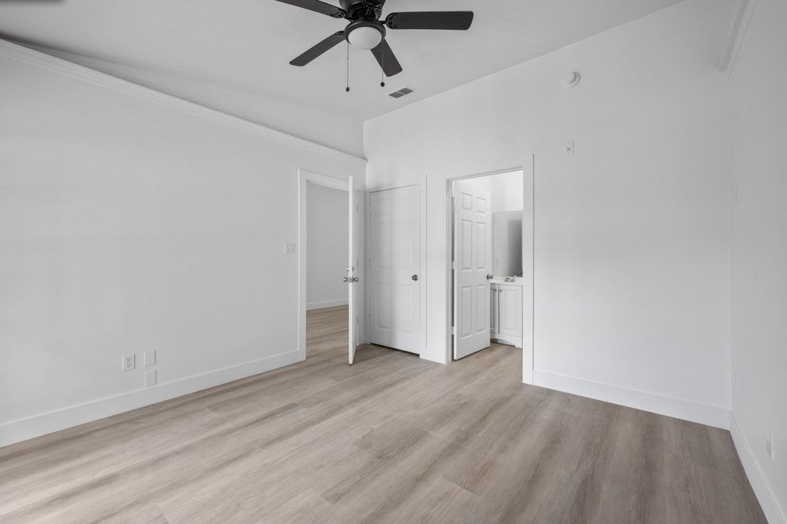 An empty bedroom with hardwood floors and a ceiling fan.