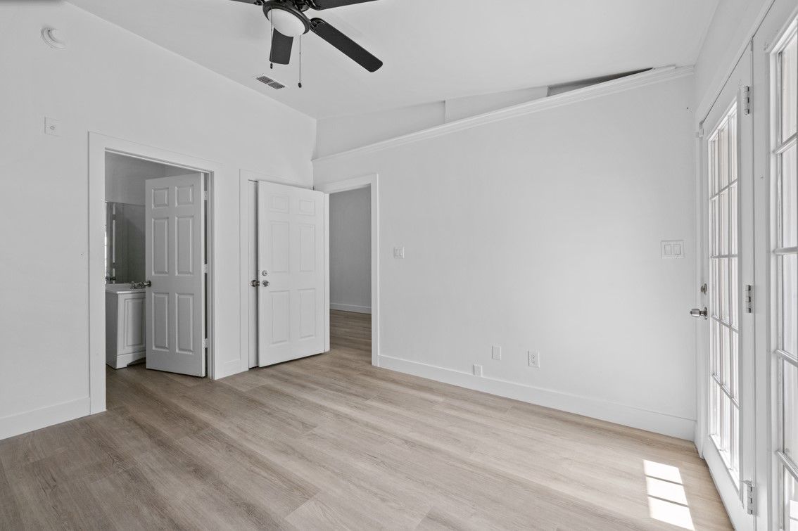 An empty room with hardwood floors and a ceiling fan.