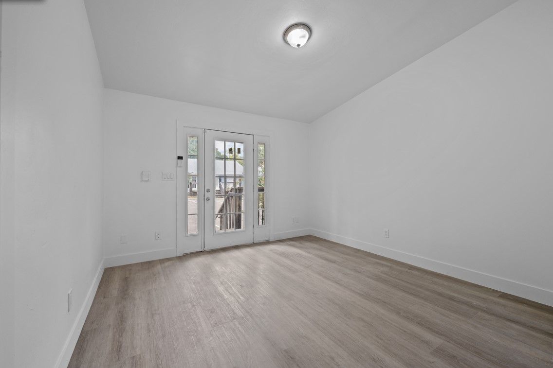 An empty room with hardwood floors and a sliding glass door.