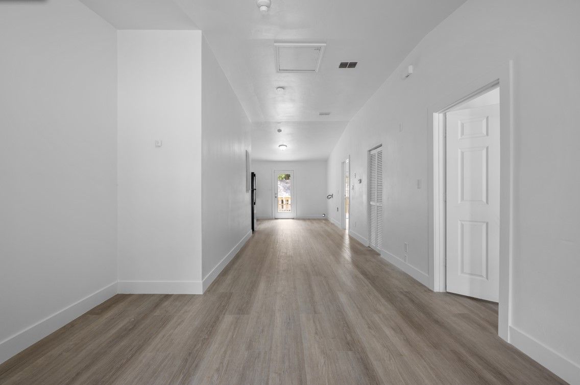 An empty hallway with hardwood floors and white walls.